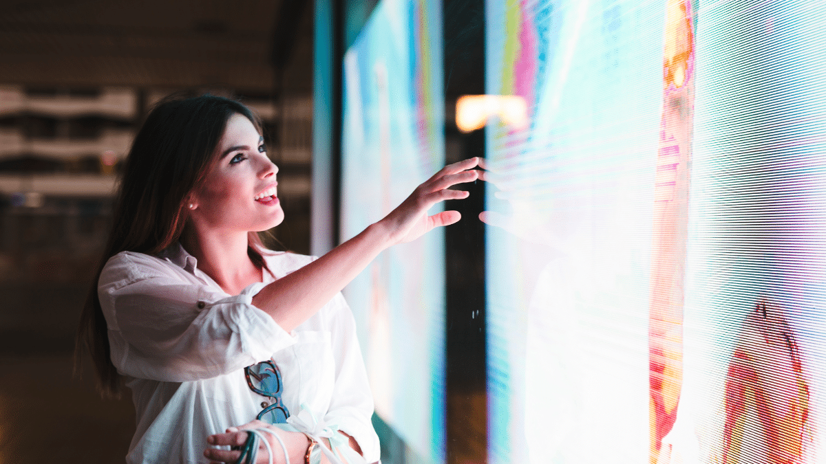 Femme interagissant avec un écran LED en vitrine (affichage dynamique retail)